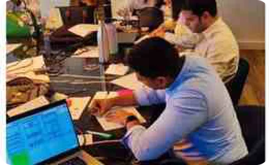 Fotografía de participantes trabajando con papeles y laptops durante la sesión presencial.